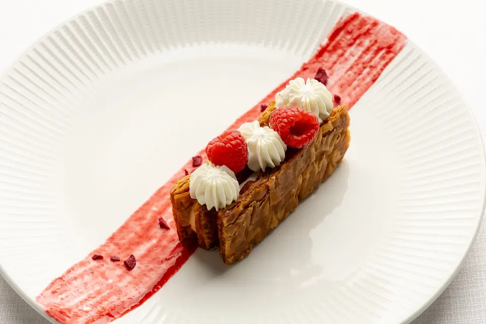 Palmera frente a un edificio histórico con detalles ornamentales y una torre circular bajo un cielo azul.