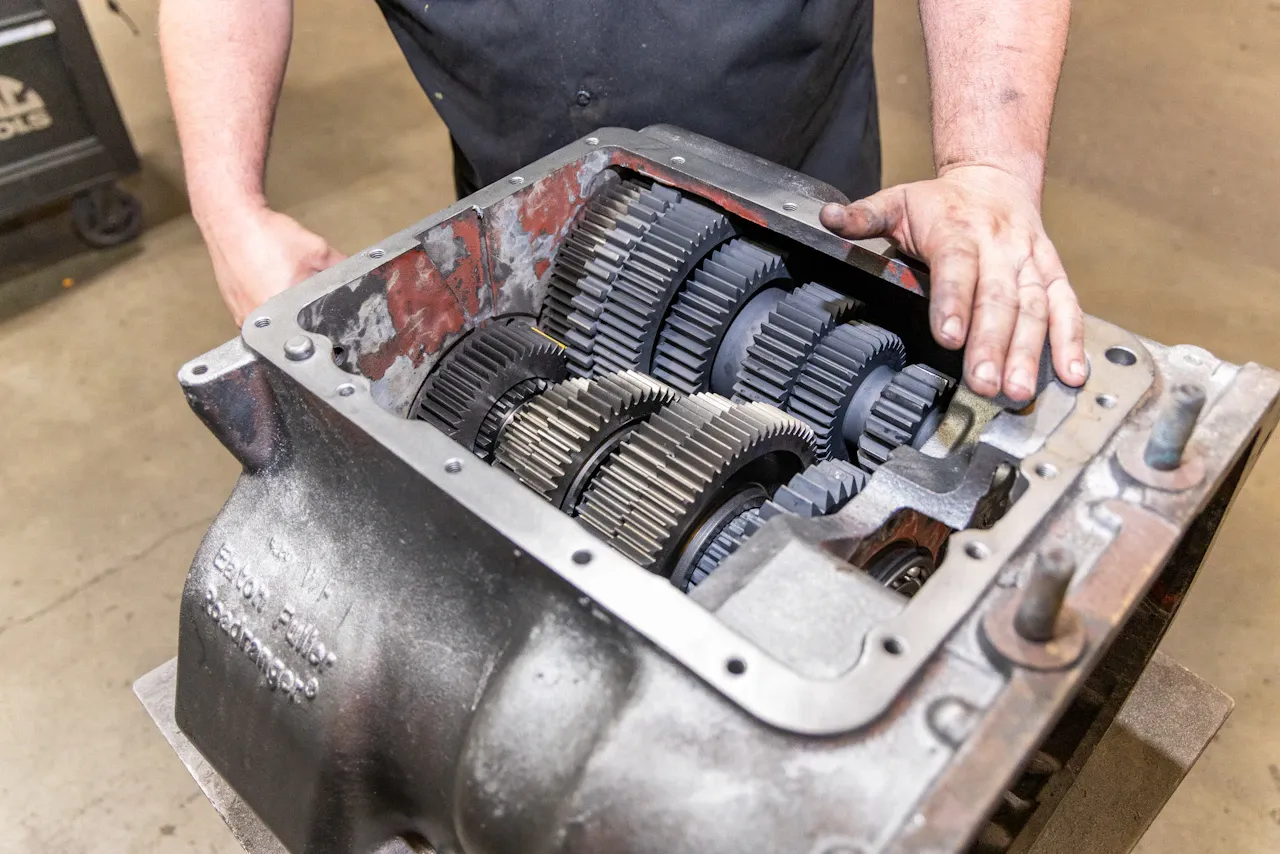 Transmission repair on a heavy-duty truck with exposed gearbox gears during inspection and maintenance service.