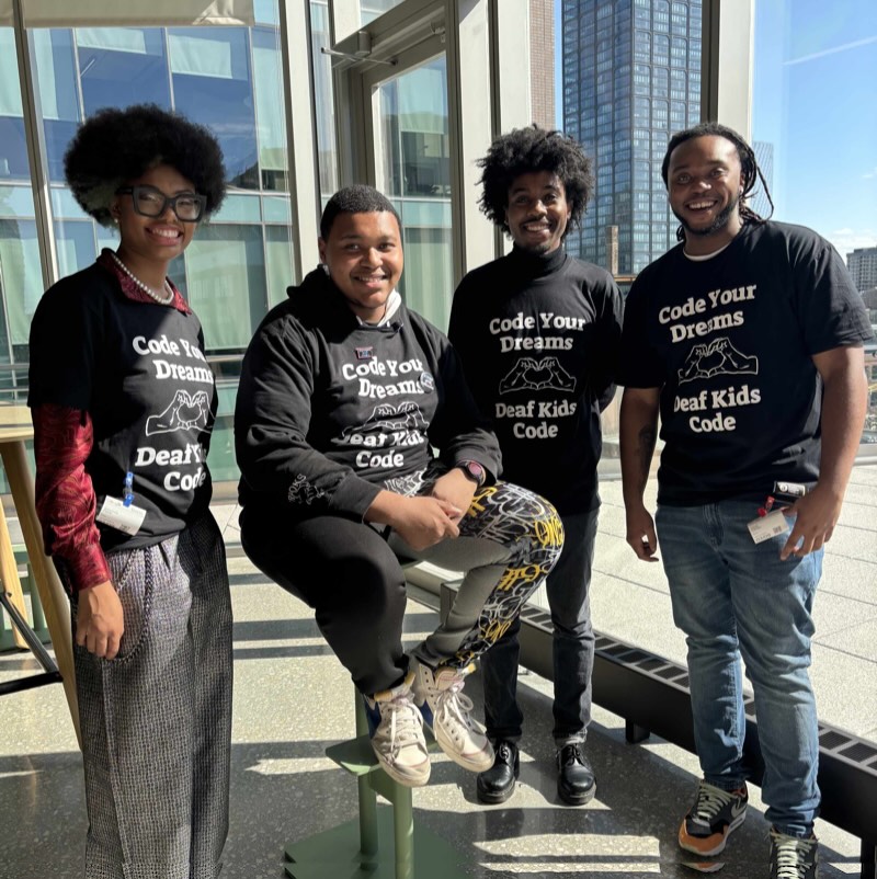 4 young students wearing code your dreams t-shirts in a downtown scene