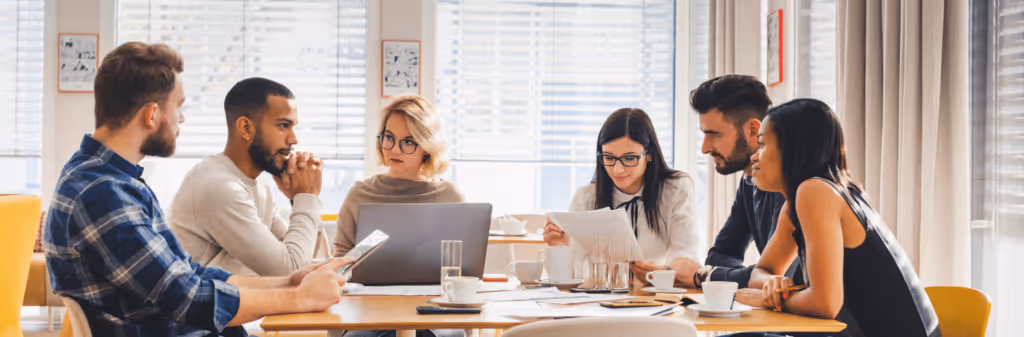 Team of employees discussing company travel policies during a meeting on how to encourage sustainable business travel choices.