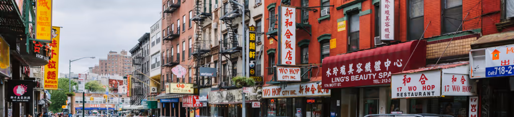 A city street lined with buildings and shops featuring signs in Chinese characters and bright colors.