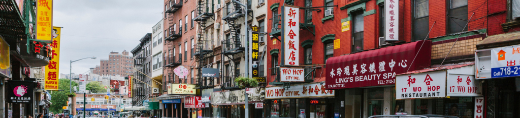 A city street lined with buildings and shops featuring signs in Chinese characters and bright colors.