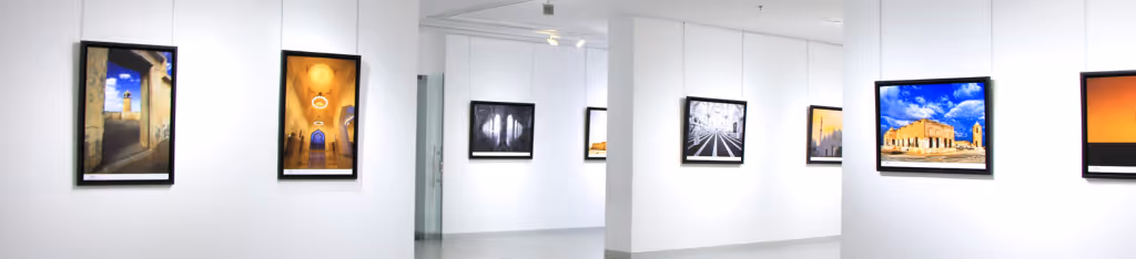 Art gallery with framed photographs on white walls, featuring landscapes and architectural scenes.