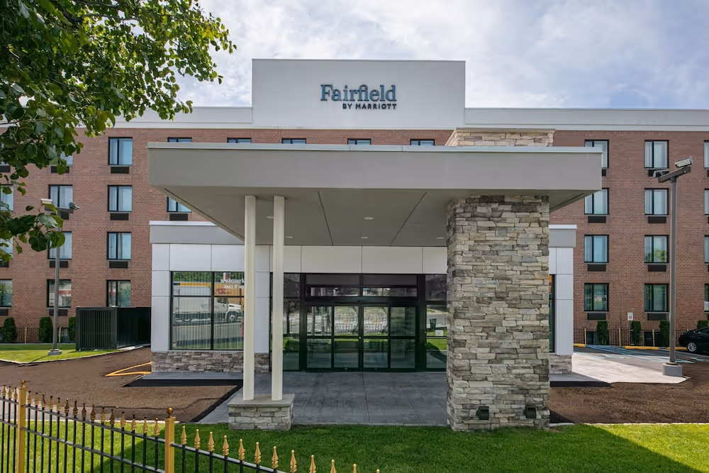 Front entrance of a Fairfield by Marriott hotel with stone pillars and large glass doors.