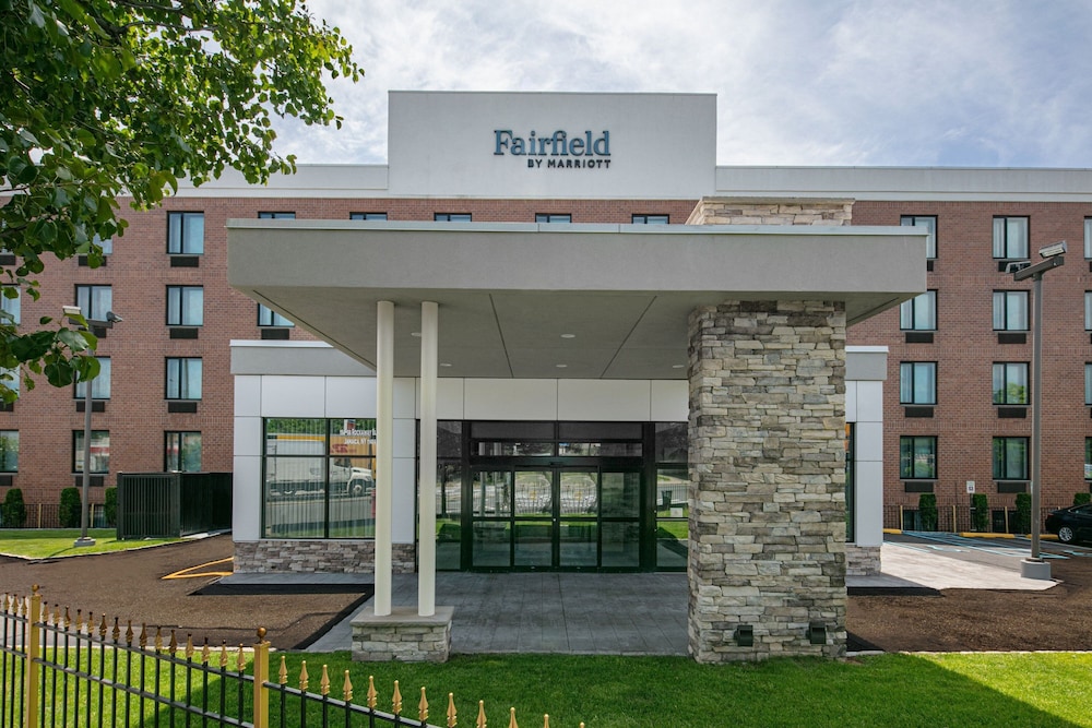 Front entrance of a Fairfield by Marriott hotel with stone pillars and large glass doors.
