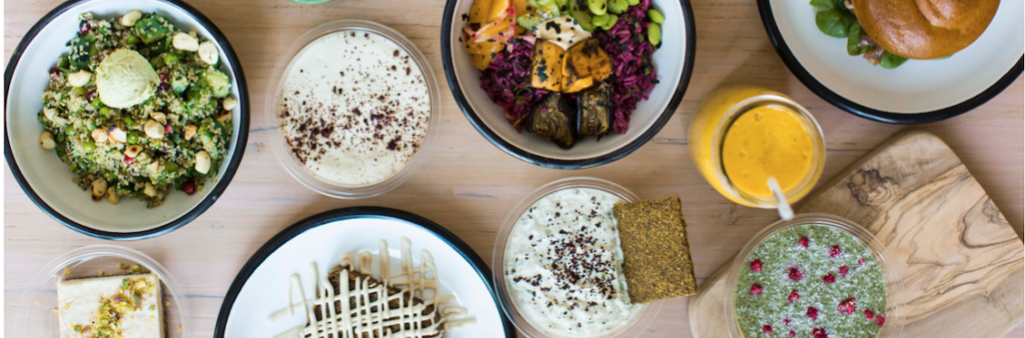 Various colorful dishes and drinks are arranged on a wooden table, showcasing diverse, fresh foods.