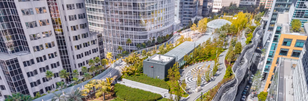 Aerial view of a rooftop park surrounded by tall office buildings in a city.
