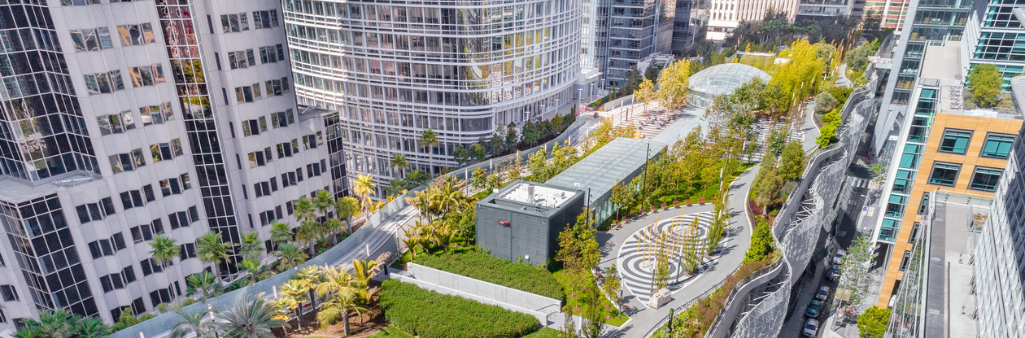 Aerial view of a rooftop park surrounded by tall office buildings in a city.