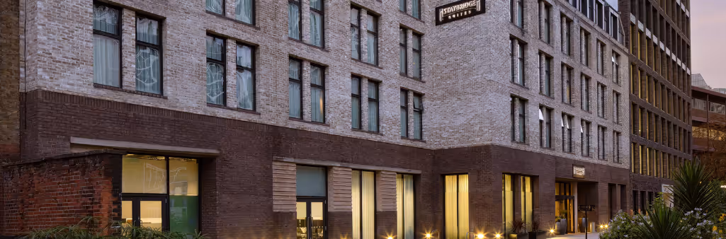 Modern brick hotel exterior with large windows, ground-level lights, and a sign reading Residence Inn.