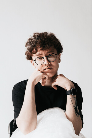 Contemplates a young guy with curly hair and glasses