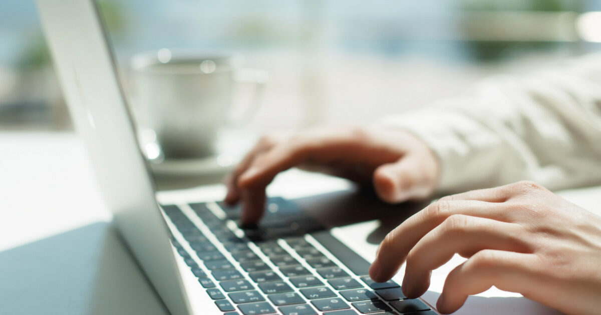 Hände, die auf dem Laptop tippen