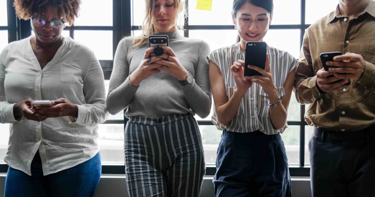 Quatre personnes regardent leur téléphone portable au bureau