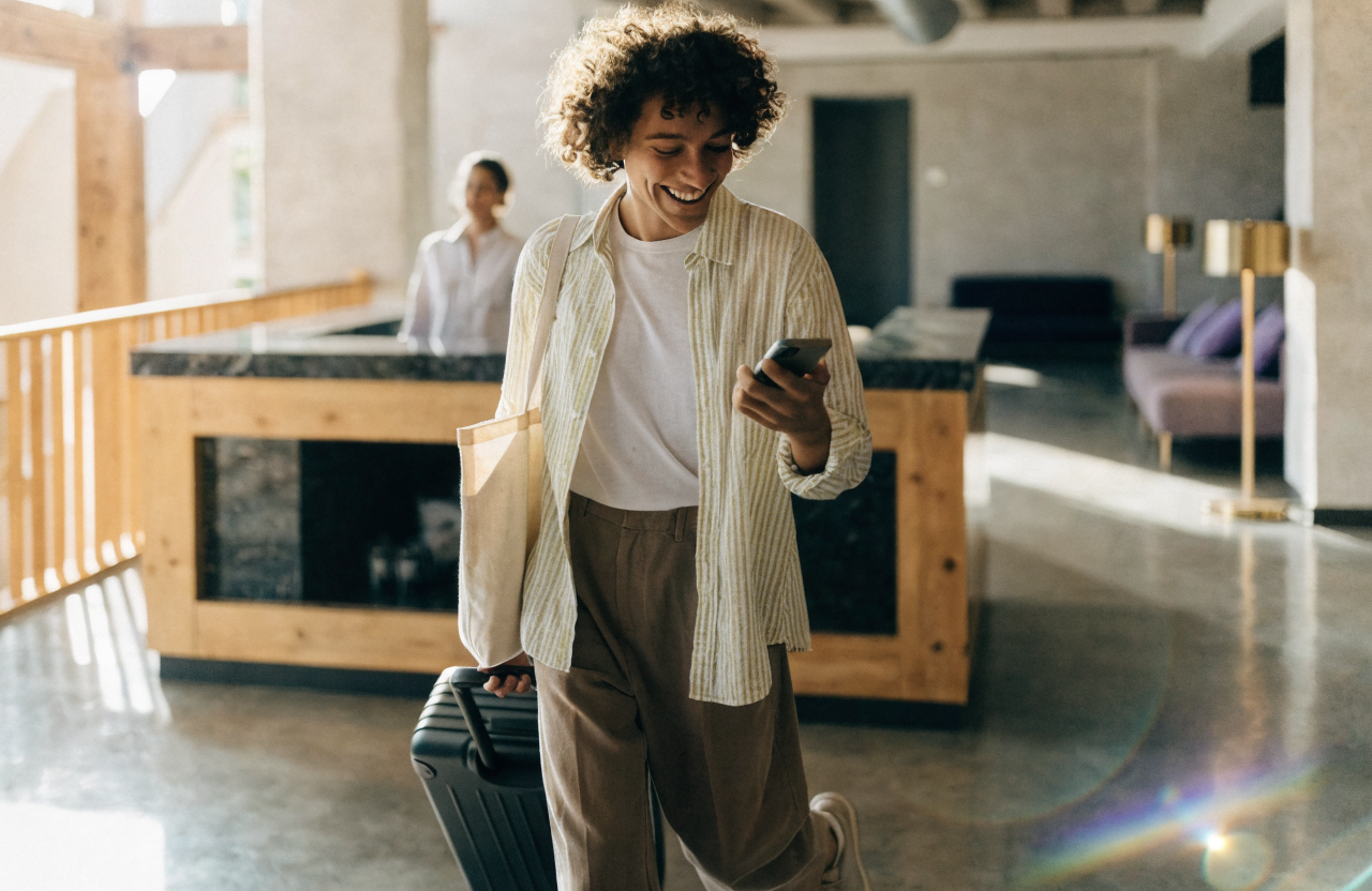 Smiling traveler checking in at a modern boutique hotel while holding a smartphone