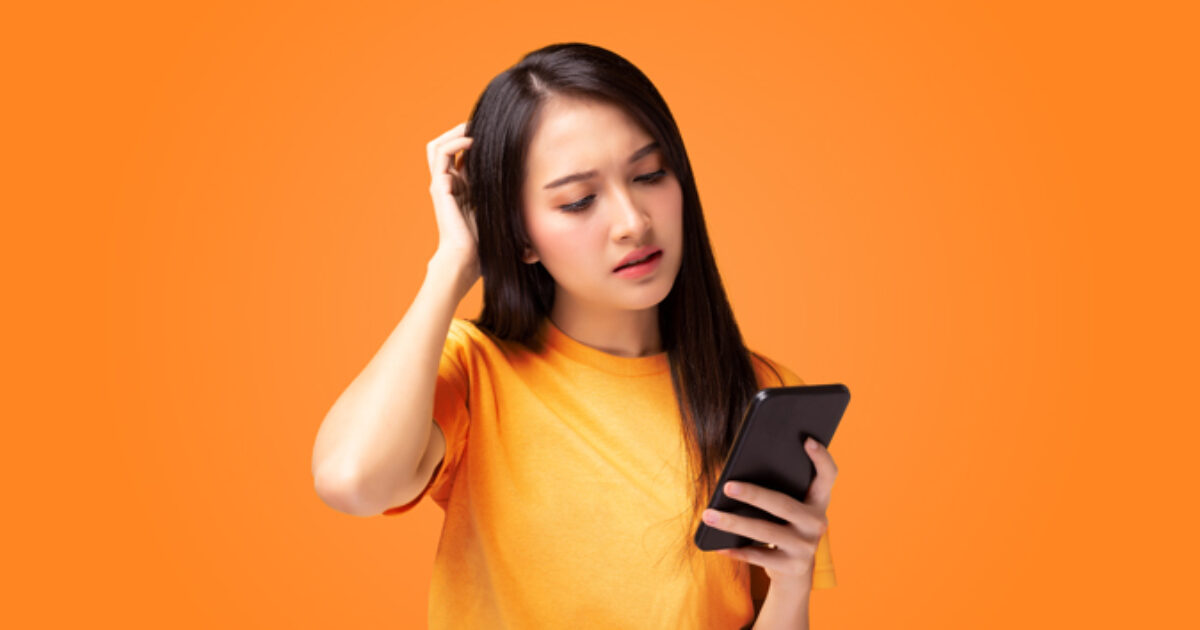 Woman scratching her head while looking at the phone