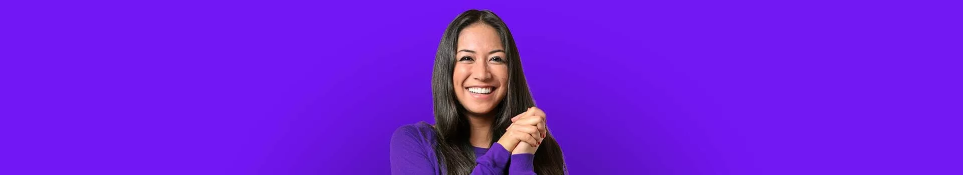 Smiling woman with hands clasped against a purple background