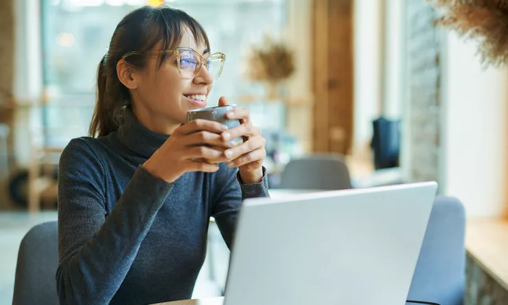 Femme tenant une tasse de café regardant par la fenêtre