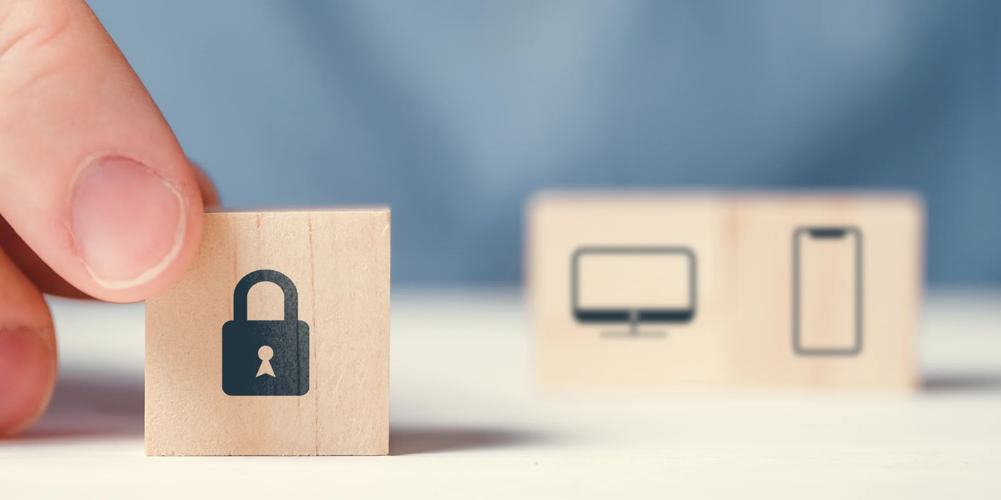 Finger holding security block with mobile and desktop blocks behind.