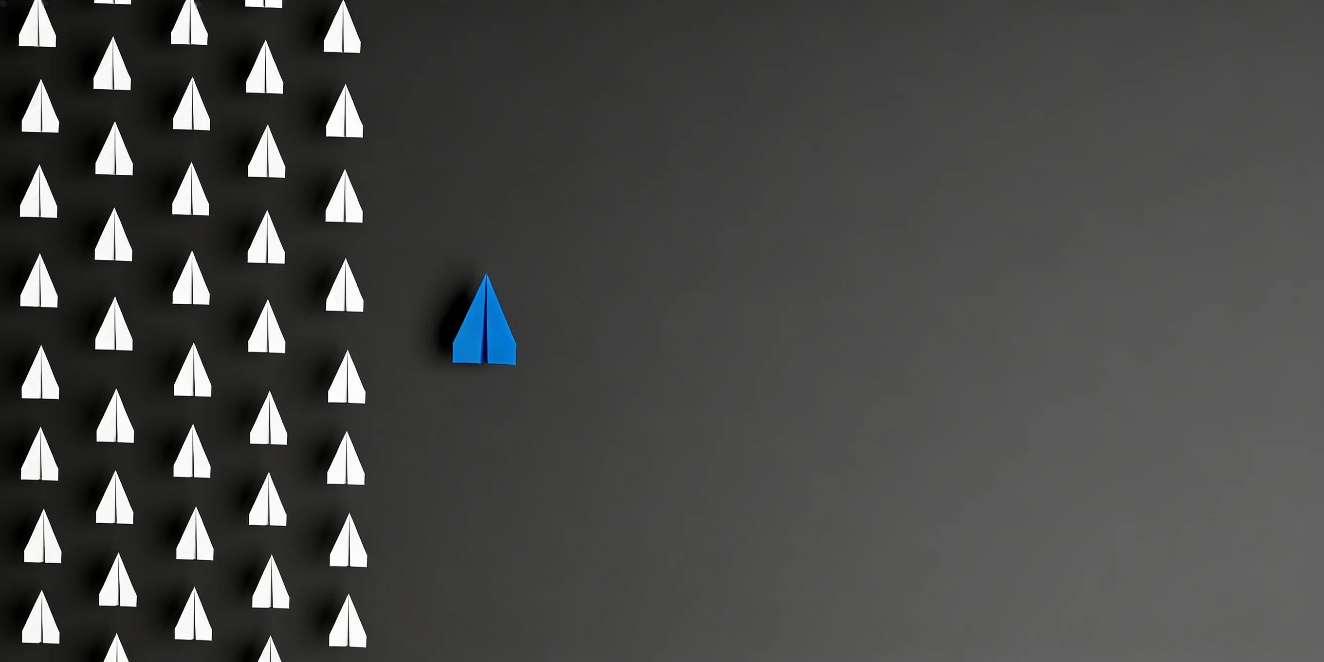 Blue paper airplane standing out against many