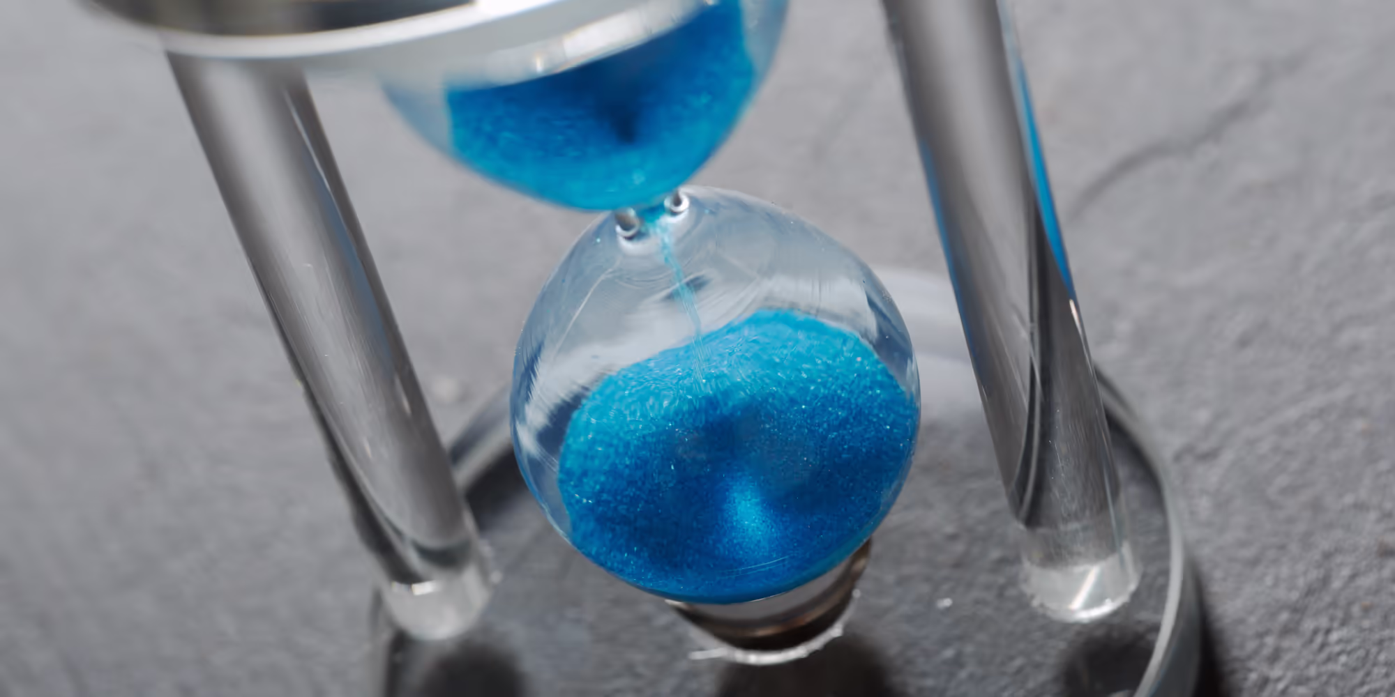 An hourglass with blue sand falling through.