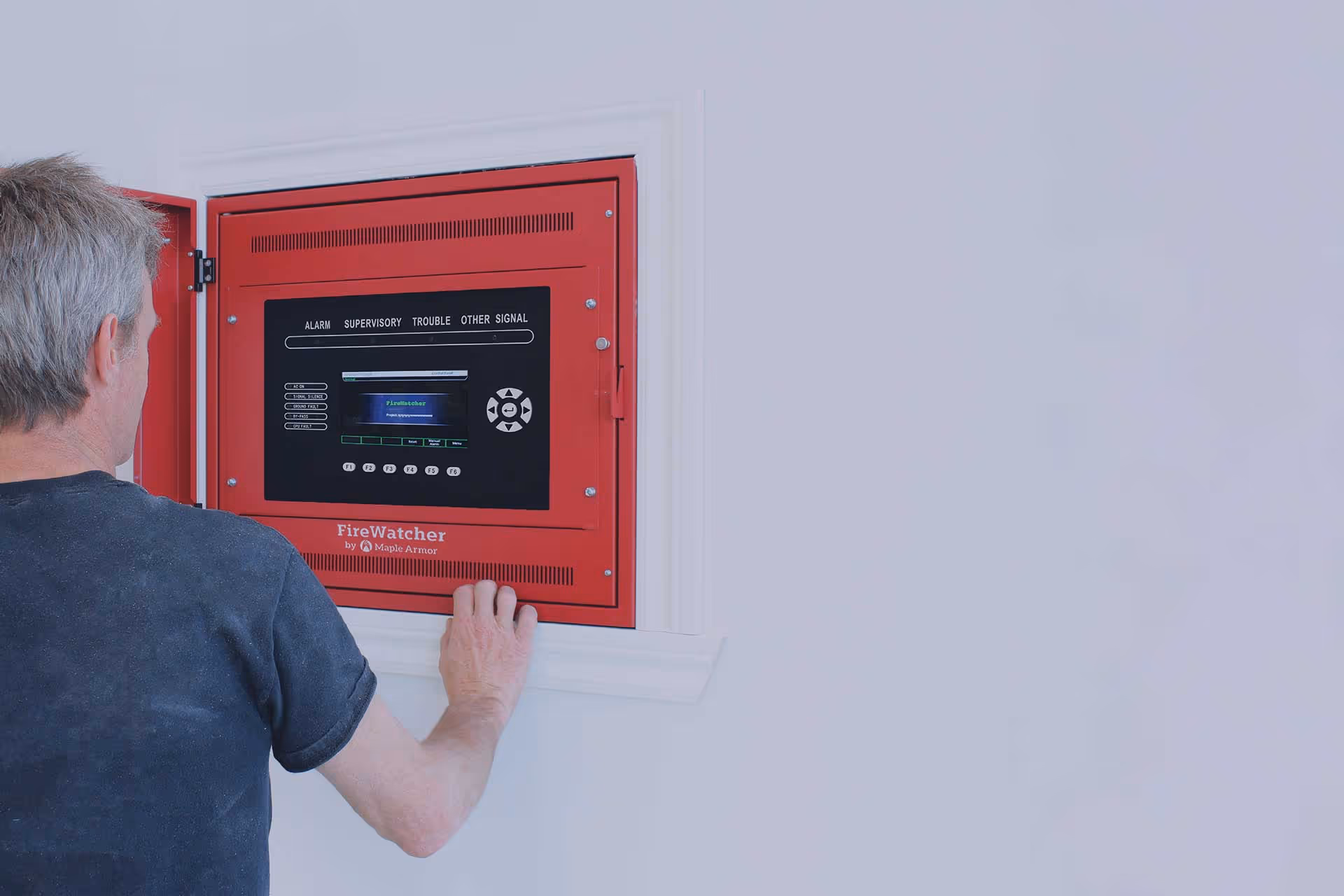 A man interacting with a Maple Armor fire safety control panel.
