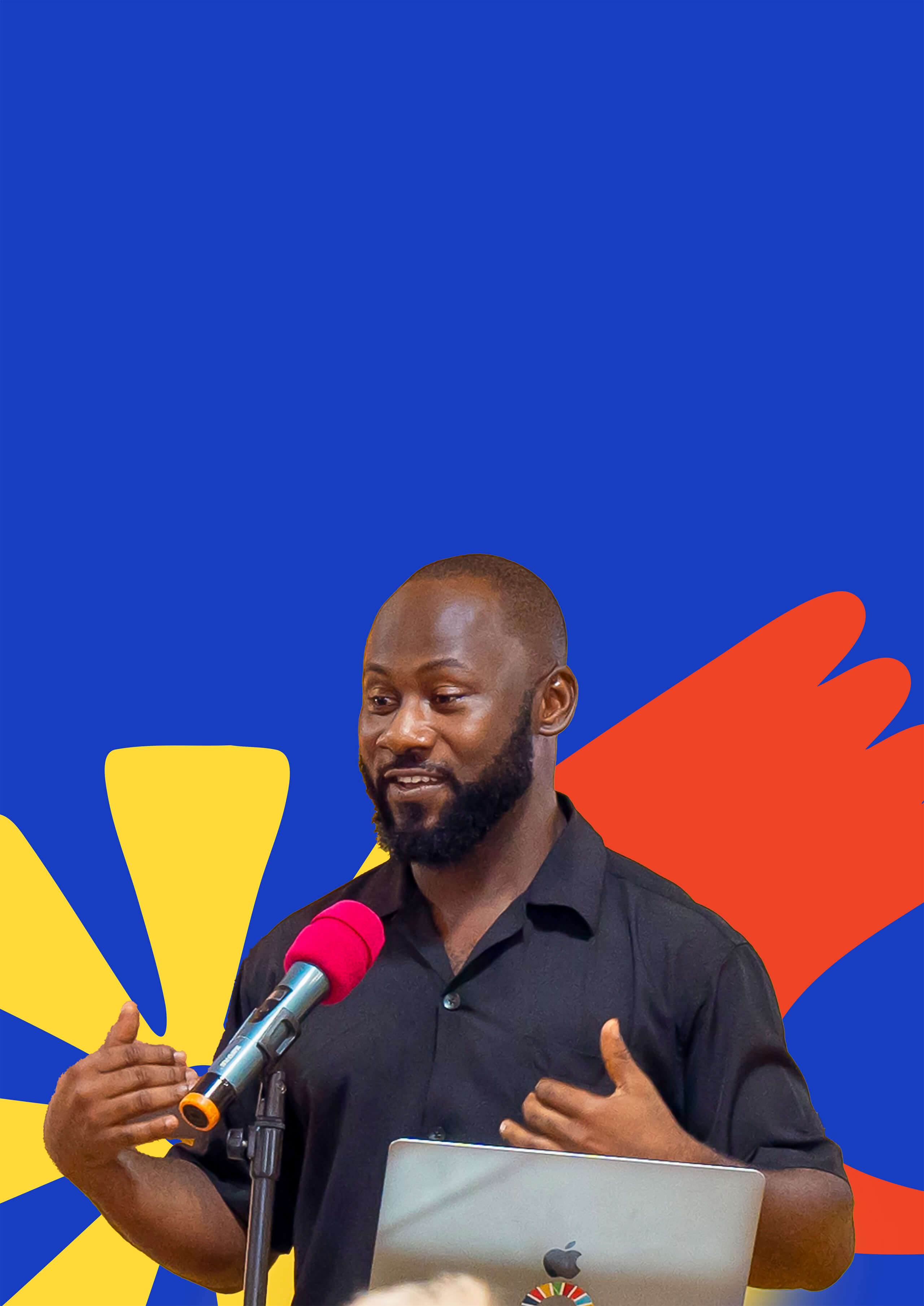 Man with beard speaking into microphone in front of a laptop against a colorful abstract background.