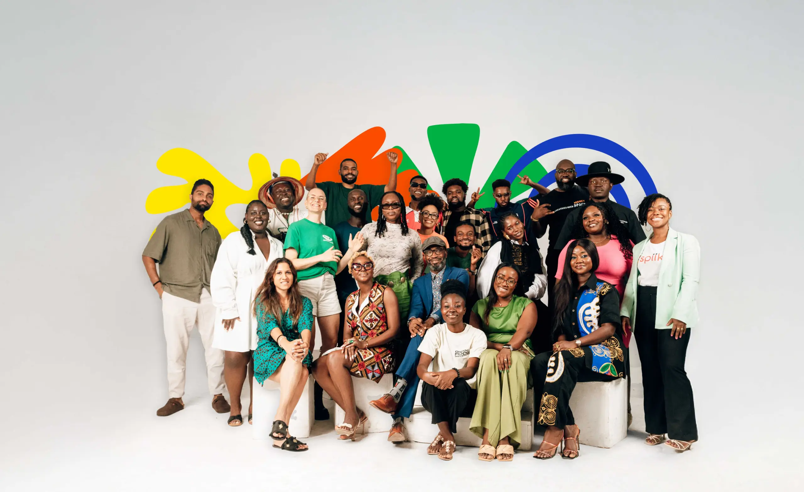 Group of diverse young adults posing together in front of colorful abstract shapes on a white background.