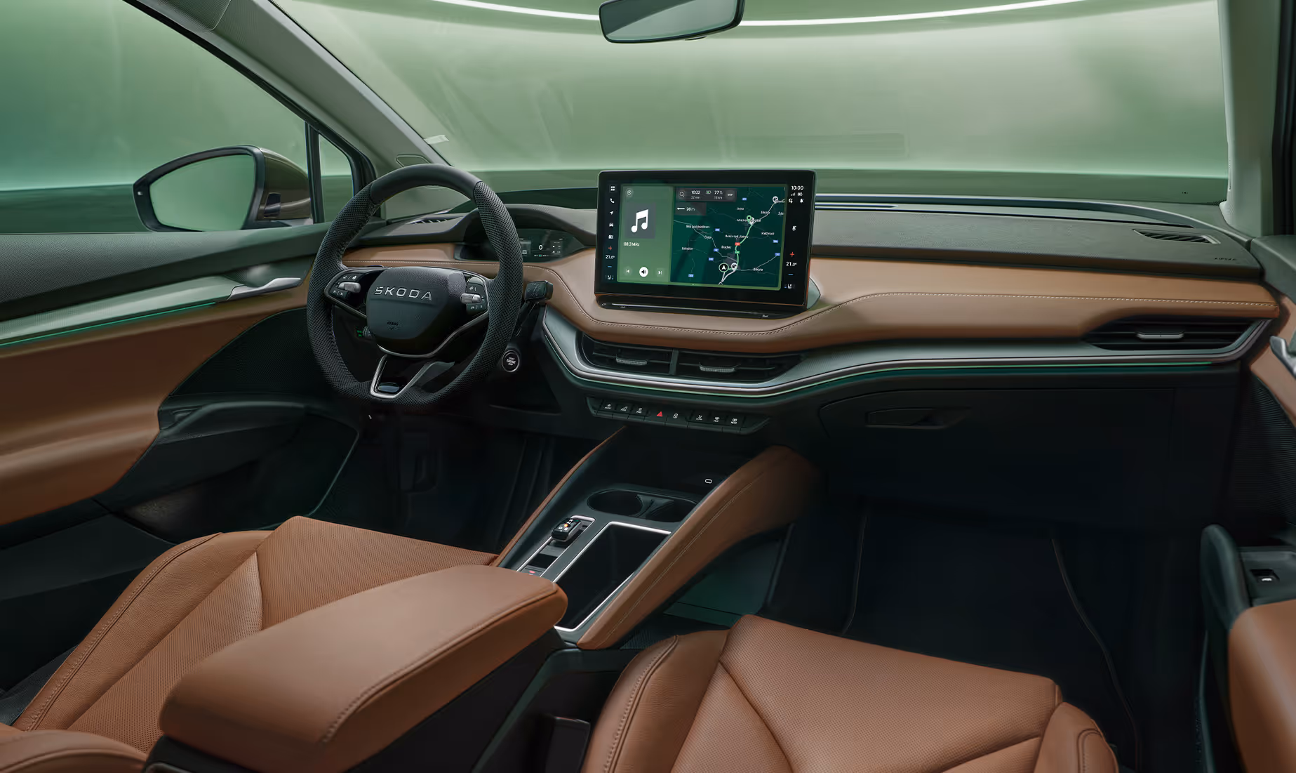 Innenansicht des Cockpits des Škoda Enyaq. Das Interieur ist mit braunem Leder und dunklen Materialien gestaltet. In der Mitte des Armaturenbretts befindet sich ein großer Infotainment-Bildschirm, der eine Navigationskarte anzeigt. Im unteren rechten Bildbereich steht auf einer dunkelgrün abgesetzten Fläche der Schriftzug „Smarte Details“.