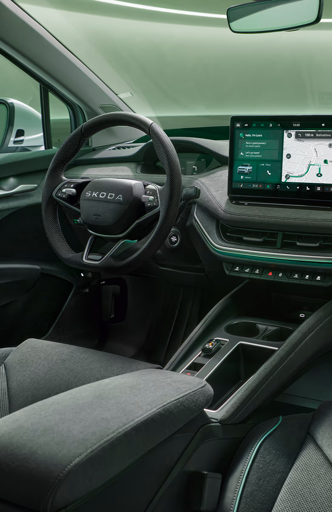 Fokus auf das Armaturenbrett und das Infotainmentsystem des Škoda Enyaq. Zentral platziert ist das freistehende 13-Zoll-Infotainmentdisplay, das eine Navigationskarte und diverse Fahrzeugfunktionen anzeigt. Das dunkle Interieur der Design Selection „Lodge“ wird durch eine grüne Ambientebeleuchtung abgerundet. Unten rechts steht auf einer dunkelgrün abgesetzten Fläche der Schriftzug "Škoda Connect".