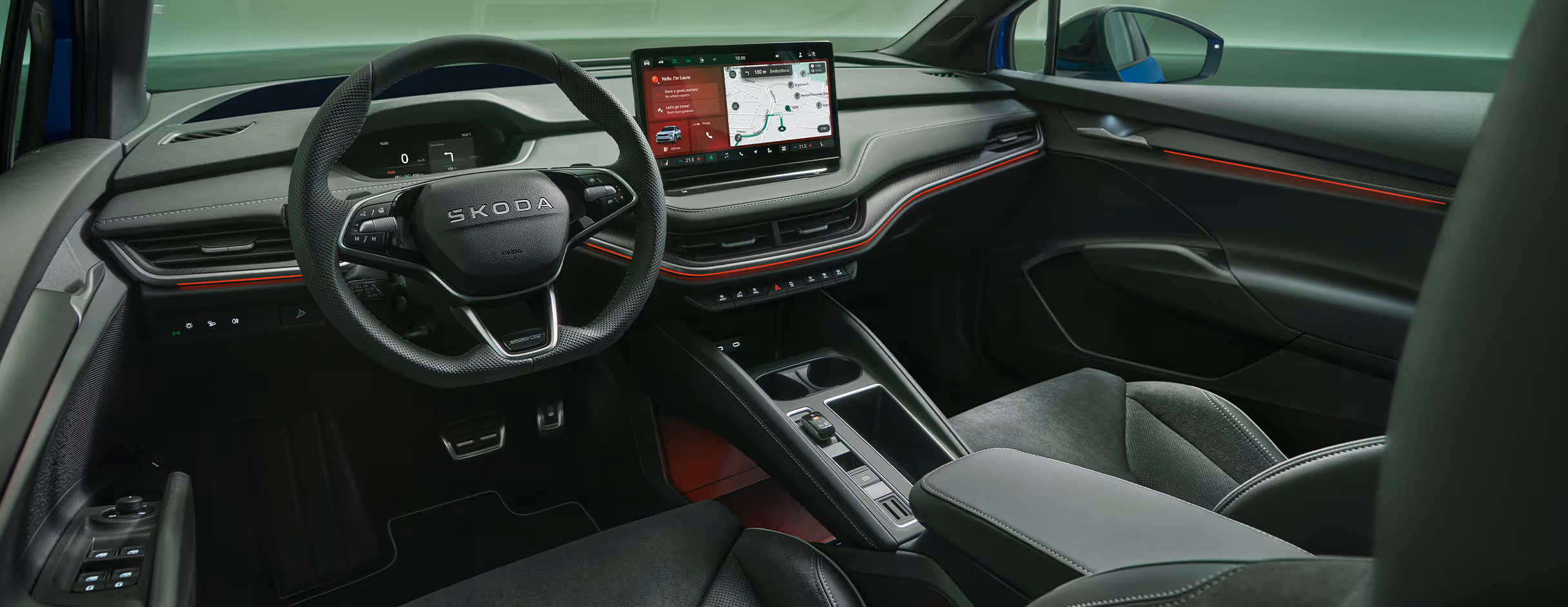 Blick aus der Fahrerperspektive in den sportlichen Innenraum des Škoda Enyaq in der Ausstattungslinie Sportline. Das schwarze Interieur mit Sportsitzen in Mikrofaser-Leder-Kombination wird durch rote Ambientebeleuchtung dynamisch in Szene gesetzt.