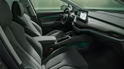 Ein Blick in den vorderen Innenraum des Škoda Enyaq mit Fokus auf den Fahrer- und Beifahrersitz. Das Interieur der Design Selection „Lounge“ überzeugt durch seine kontrastreiche Mischung aus grau und schwarz im Modern-Solid-Design sowie einer grünen Ambientebeleuchtung.