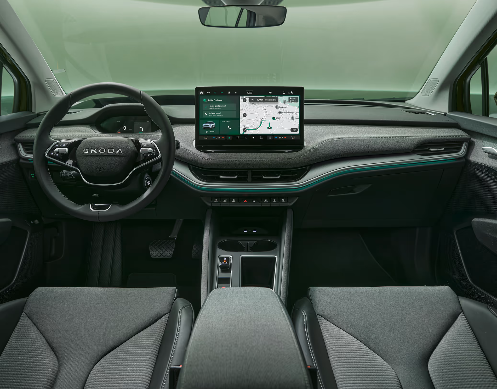 Eine symmetrische Weitwinkelaufnahme zeigt das Cockpit des Škoda Enyaq aus der Perspektive der Rücksitze. Das elegante Interieur der Design Selection „ecoSuite“ besticht durch nachhaltig gegerbtes, cognacfarbenes Leder, akzentuiert durch eine Dekorleiste in Piano-Schwarz und eine grüne Ambientebeleuchtung.