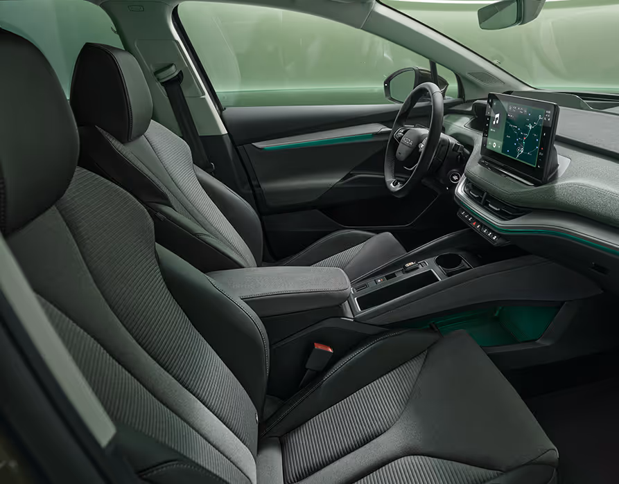 Ein Blick in den vorderen Innenraum des Škoda Enyaq RS mit Fokus auf den Fahrer- und Beifahrersitz. Das Interieur der Design Selection „RS Lounge“ überzeugt durch perforierte schwarze Lederbezüge und Dekor in Carbon-Optik sowie grüne Ambientebeleuchtung.