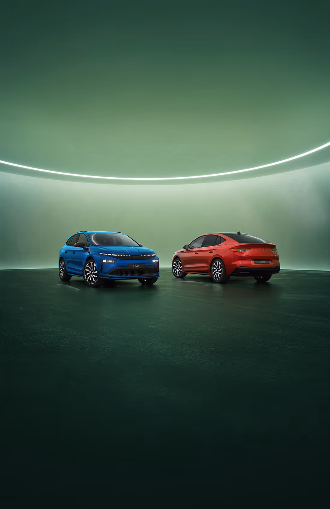 Zwei Škoda Enyaq Modelle der Sportline-Ausstattungslinie vor grünen Studiohintergrund. Links steht ein Enyaq in der SUV-Variante in der Farbe Race-Blau Metallic mit Frontansicht, rechts ist ein Enyaq Coupé in der Farbe Velvet-Rot Premium Metallic mit abfallender Dachlinie in der Heckansicht zu sehen.