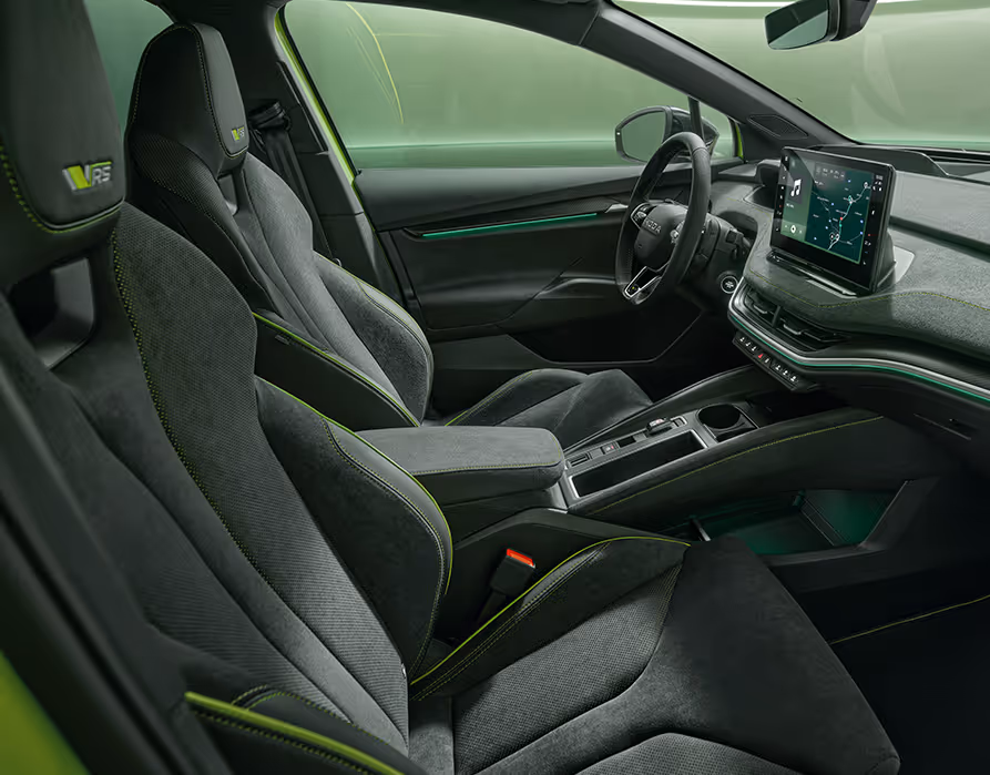Ein Blick in den vorderen Innenraum des Škoda Enyaq RS mit Fokus auf den Fahrer- und Beifahrersitz. Das Interieur der Design Selection „RS Lounge“ überzeugt durch perforierte schwarze Lederbezüge und Dekor in Carbon-Optik sowie grüne Ambientebeleuchtung.