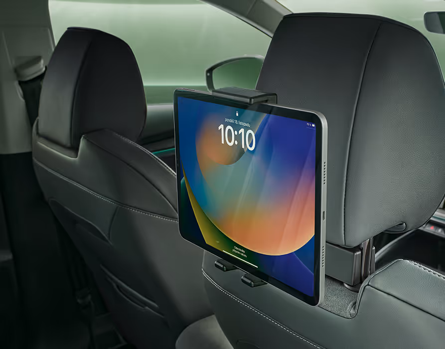 Blick von der Rückbank eines Škoda Enyaq nach vorn in das Cockpit, das in der Design Selection Loft gehalten ist. An den Kopfstützen der Vordersitze sind zwei Multimediahalter befestigt, in denen jeweils ein Tablet steckt. Im Hintergrund sind das Armaturenbrett mit dem zentralen Infotainment-Display und das Lenkrad zu sehen.