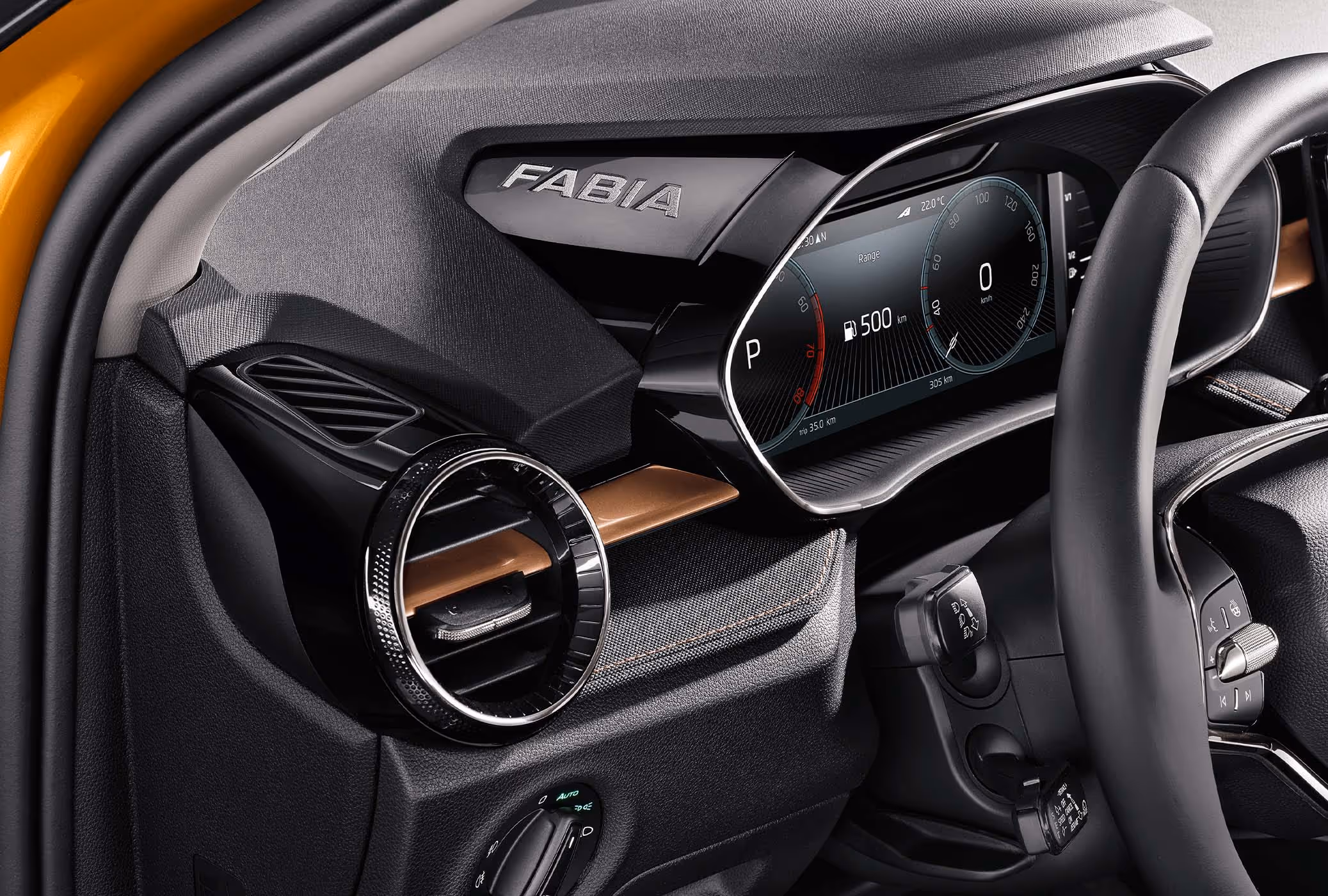 Detailansicht des Fahrer-Cockpits eines Škoda Fabia, die das digitale Kombiinstrument (Virtual Cockpit) unter der Hutze mit dem seitlichen „FABIA“-Schriftzug zeigt. Links daneben befinden sich eine runde Lüftungsdüse mit Chrom-Akzenten und eine Dekorleiste in Copper, die in das mit Stoff bezogene Armaturenbrett eingelassen ist. Angeschnitten ist zudem das Multifunktionslenkrad mit Bedienelementen.
