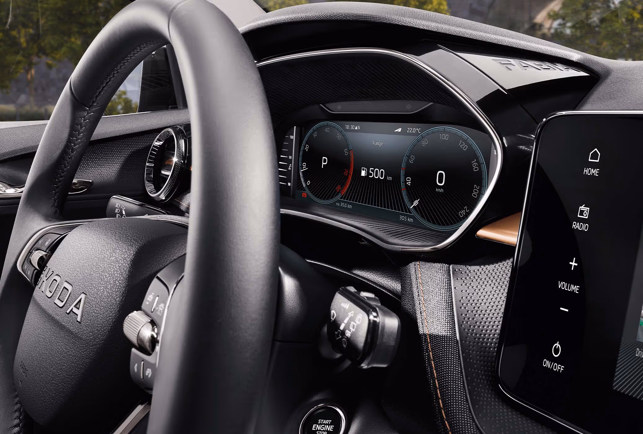 Nahaufnahme des Zweispeichen-Multifunktionslenkrads und des dahinterliegenden digitalen Kombiinstruments (Virtual Cockpit). Sichtbar sind zudem der Start-Stopp-Knopf an der Lenksäule sowie ein Teil des zentralen Infotainment-Displays. Das Armaturenbrett ist mit Stoff bezogen und wird durch eine Dekorleiste in Copper sowie kontrastierende Ziernähte akzentuiert.