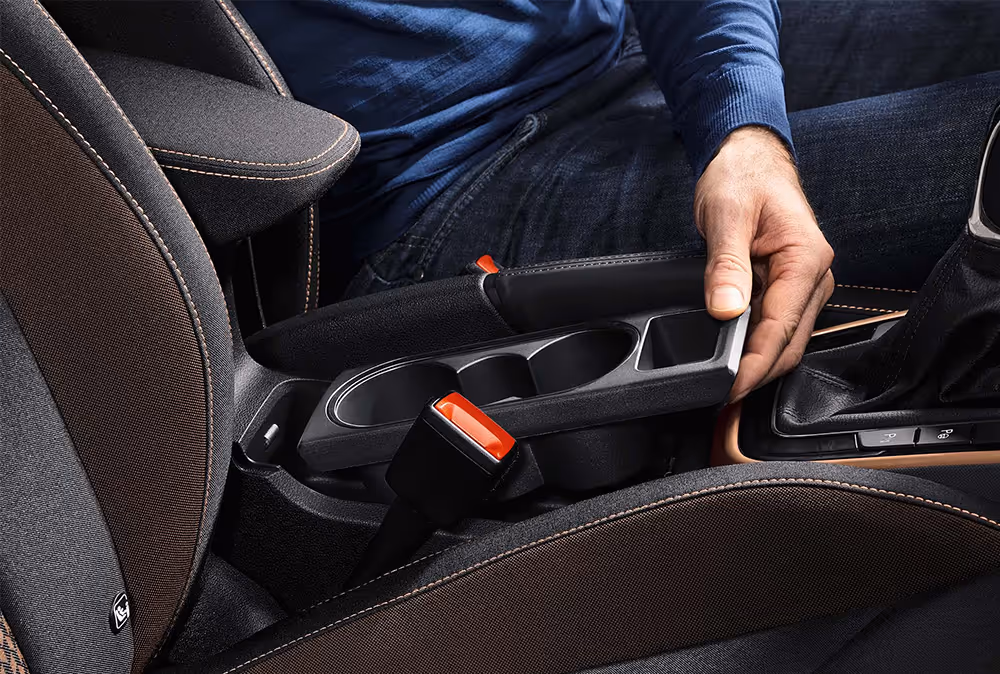Detailansicht der Mittelkonsole eines Škoda Fabia, die das Herausnehmen des flexiblen Doppel-Getränkehalters demonstriert. Dieses praktische „Simply Clever“-Feature ermöglicht eine variable Nutzung des Stauraums zwischen den Vordersitzen.