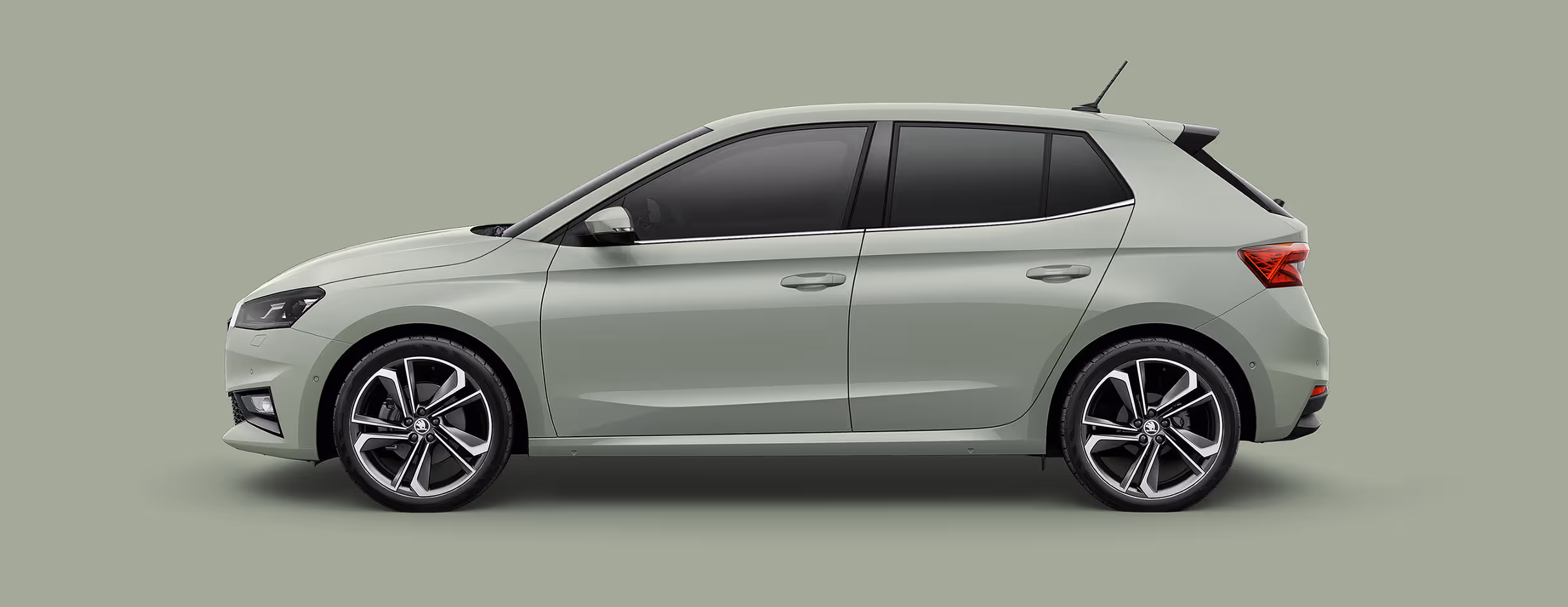 Seitenansicht eines Škoda Fabia in der Lackierung Timiano-Grün mit 18 Zoll Leichtmetallfelgen “Libra schwarz glanzgedreht" vor einem einfarbigen Hintergrund in der Farbe der Fahrzeuglackierung.