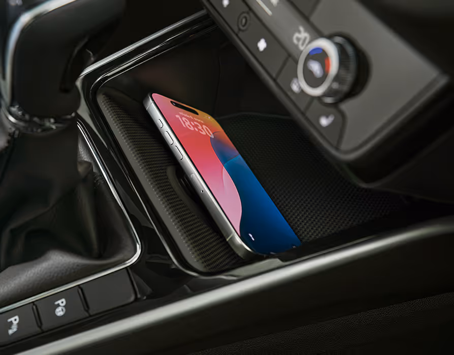 Eine Nahaufnahme der Mittelkonsole zeigt die Phonebox, in der ein Smartphone auf einer strukturierten Oberfläche liegt. Oberhalb des Ablagefachs sind zwei USB-C-Anschlüsse sowie ein Teil der Klimabedienelemente zu erkennen.