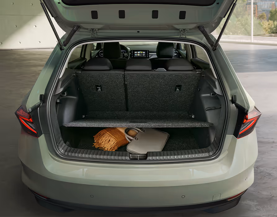 Eine Ansicht in den geöffneten Kofferraum des Škoda Fabia zeigt den variablen Ladeboden, der den Gepäckraum horizontal in zwei Ebenen unterteilt. Im unteren Bereich liegen eine helle Tasche und ein textiles Accessoire, während die darüberliegende Fläche frei bleibt. Durch den Innenraum hindurch ist der Blick auf die Rücksitzbank und das Cockpit im vorderen Fahrzeugbereich möglich.