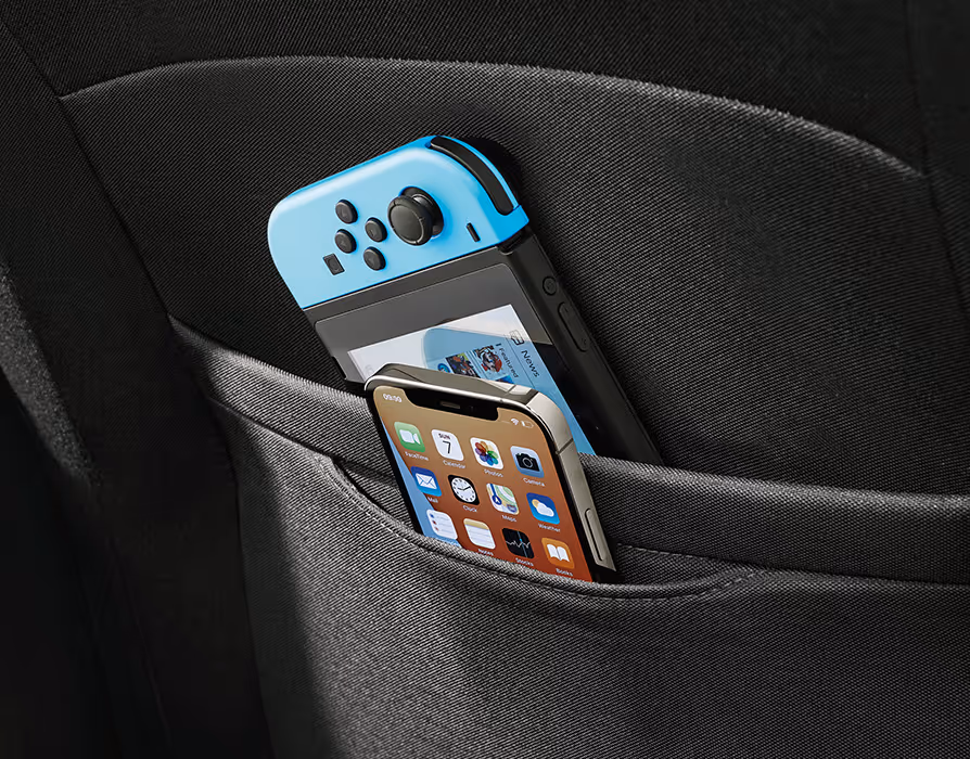 Aufnahme der Rückseite des Vordersitzes, die mit cleveren Doppeltaschen ausgestattet ist. In der Abbildung steckt eine mobile Spielekonsole in der Haupttasche, während ein Smartphone sicher in der kleineren, passgenauen Zusatztasche verstaut ist.