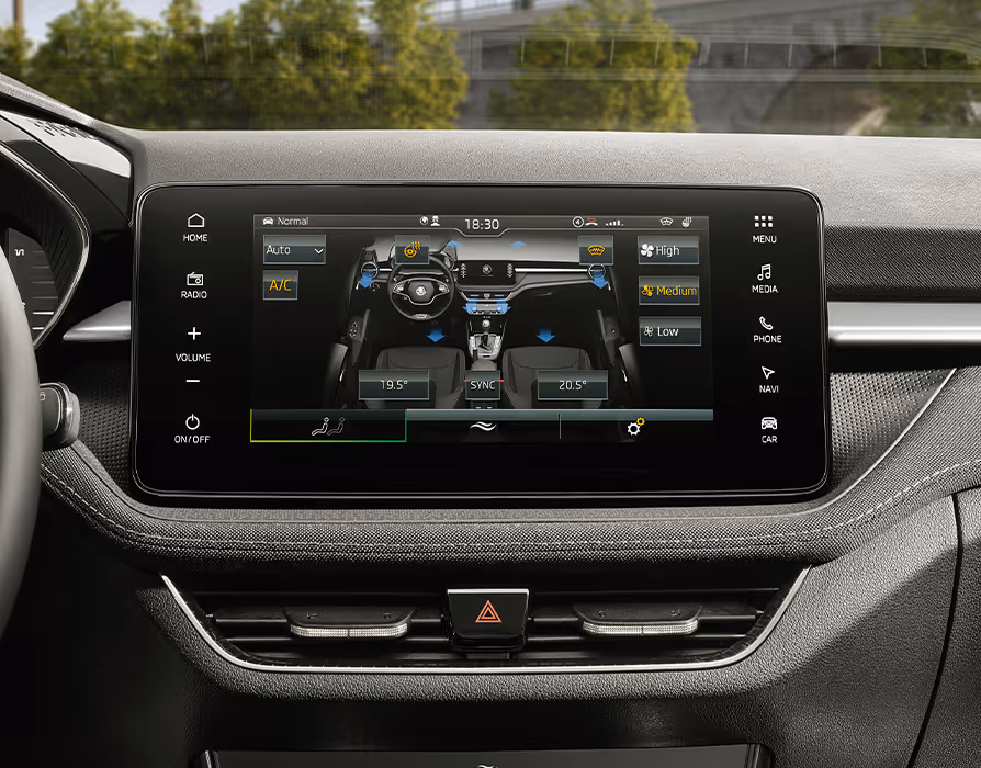 Eine Nahaufnahme des zentralen Infotainment-Displays zeigt das Menü der Klimaanlage mit einer visuellen Darstellung des Innenraums sowie den Einstellungen für Temperatur und Sitzheizung. Umgeben ist der Touchscreen von der strukturierten Oberfläche des Armaturenbretts mit sichtbaren Ziernähten. Unterhalb der Anzeige befinden sich die mittleren Lüftungsdüsen und der Schalter für die Warnblinkanlage.