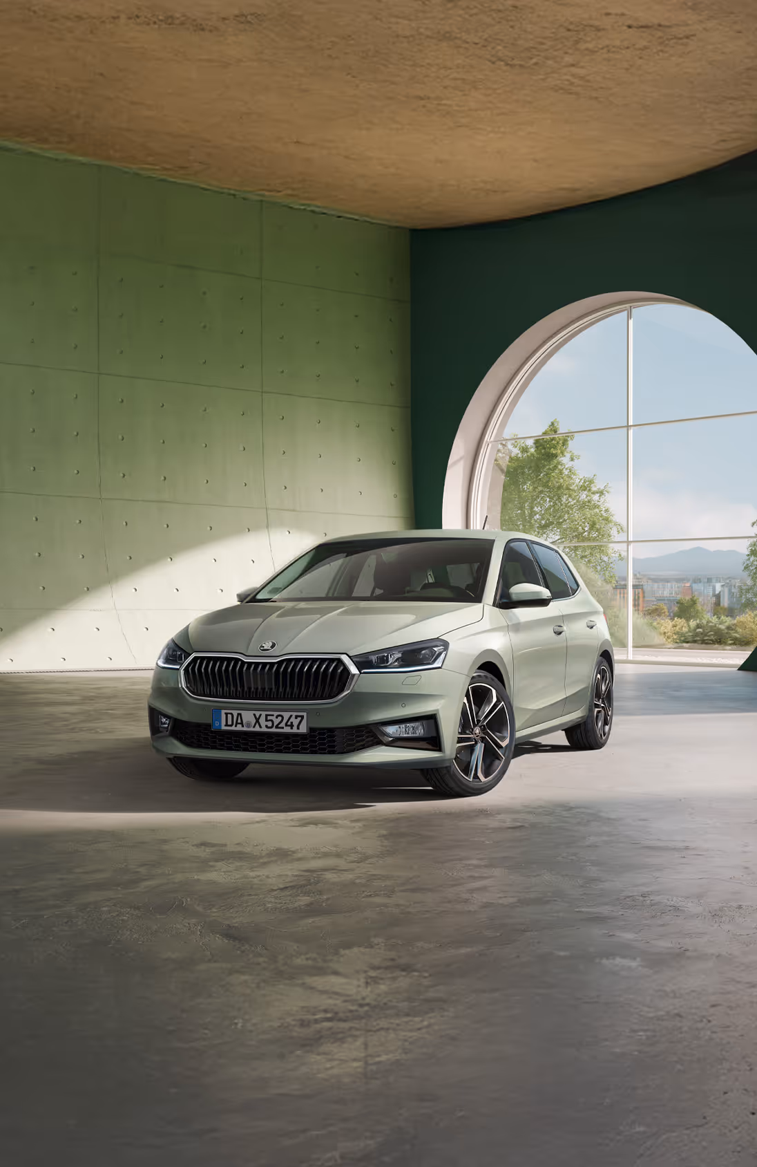 Frontalansicht des Škoda Elroq in der Farbe Timiano-Grün vor einem grünen Studiohintergrund. Die LED-Matrix-Scheinwerfer des Fahrzeugs leuchten und betonen das moderne Design der Frontpartie.