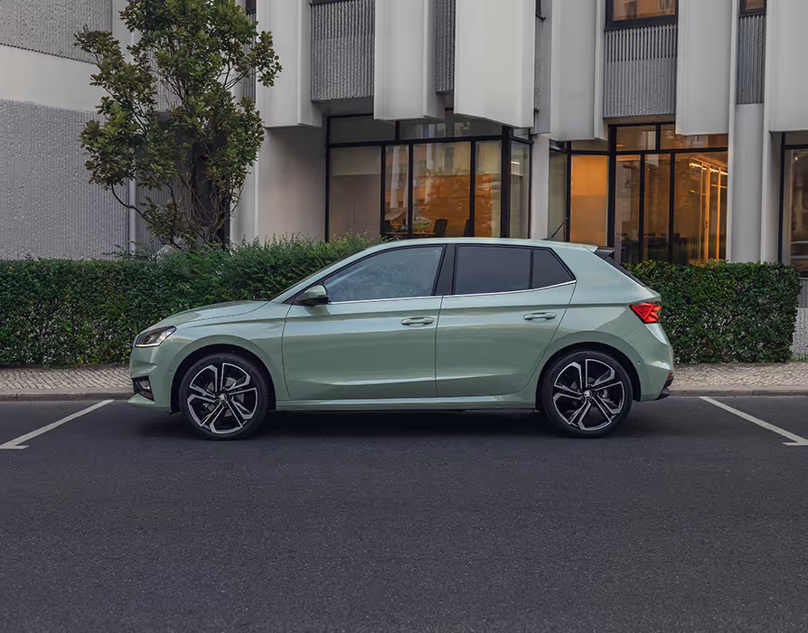 Schräge Heckansicht eines Škoda Elroq in der Farbe Timiano-Grün vor einem grünem Studiohintergrund. Die Rückleuchten und der prominente Škoda Schriftzug am Heck sind deutlich zu sehen.