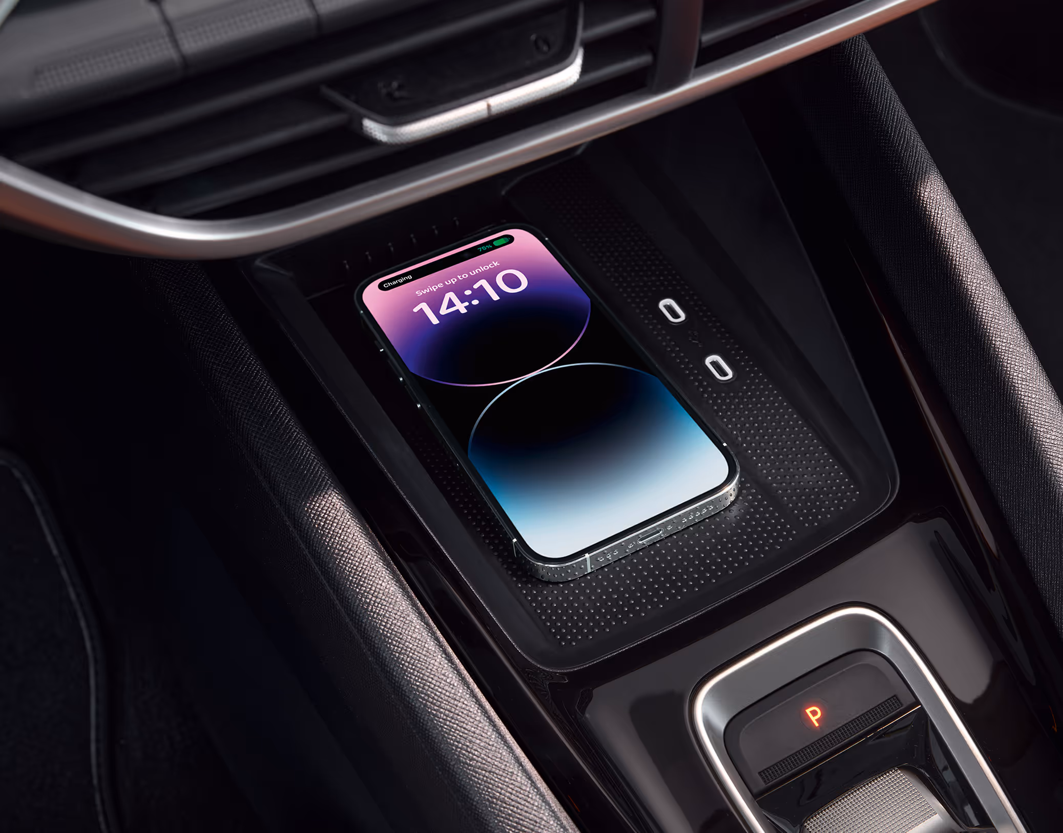 Eine Nahaufnahme zeigt die Phonebox in der Mittelkonsole eines Škoda Octavia, in der ein Smartphone kabellos geladen wird. Auf dem Bildschirm des Telefons wird der Ladevorgang und die Uhrzeit 14:10 angezeigt, während daneben der DSG-Wählhebel und USB-C-Anschlüsse zu sehen sind.
