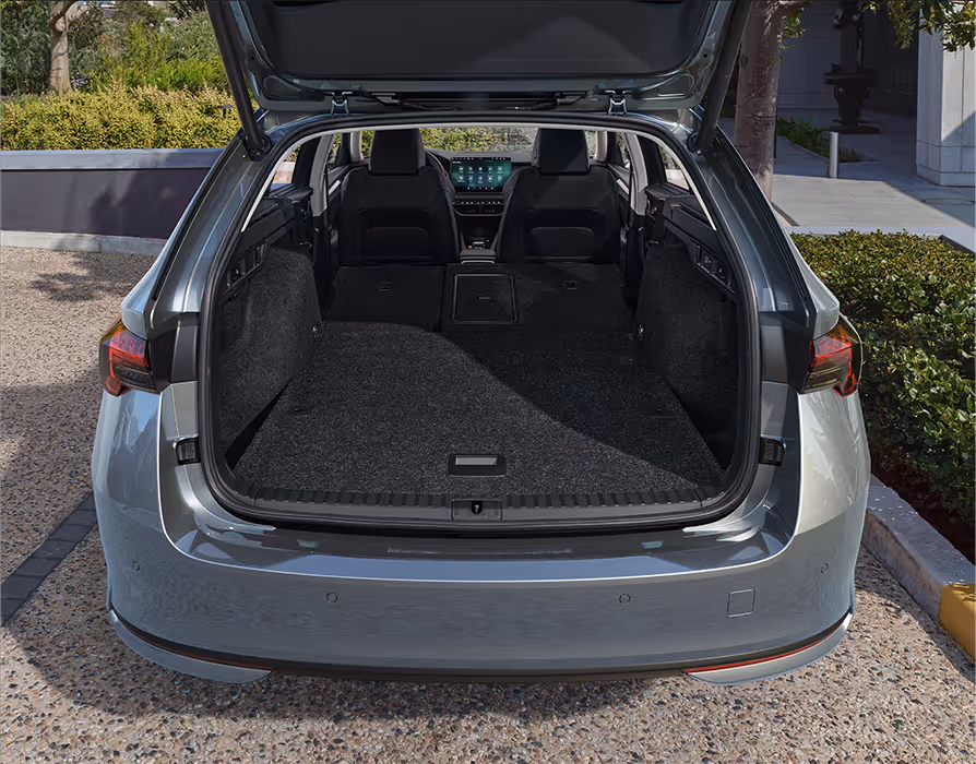 Eine Ansicht des geöffneten Kofferraums eines Škoda Octavia Combi zeigt die maximale Ladekapazität. Die Rücksitzlehnen sind umgeklappt und schaffen eine durchgehend ebene Ladefläche, die den Blick auf das Cockpit und die Vordersitze freigibt.