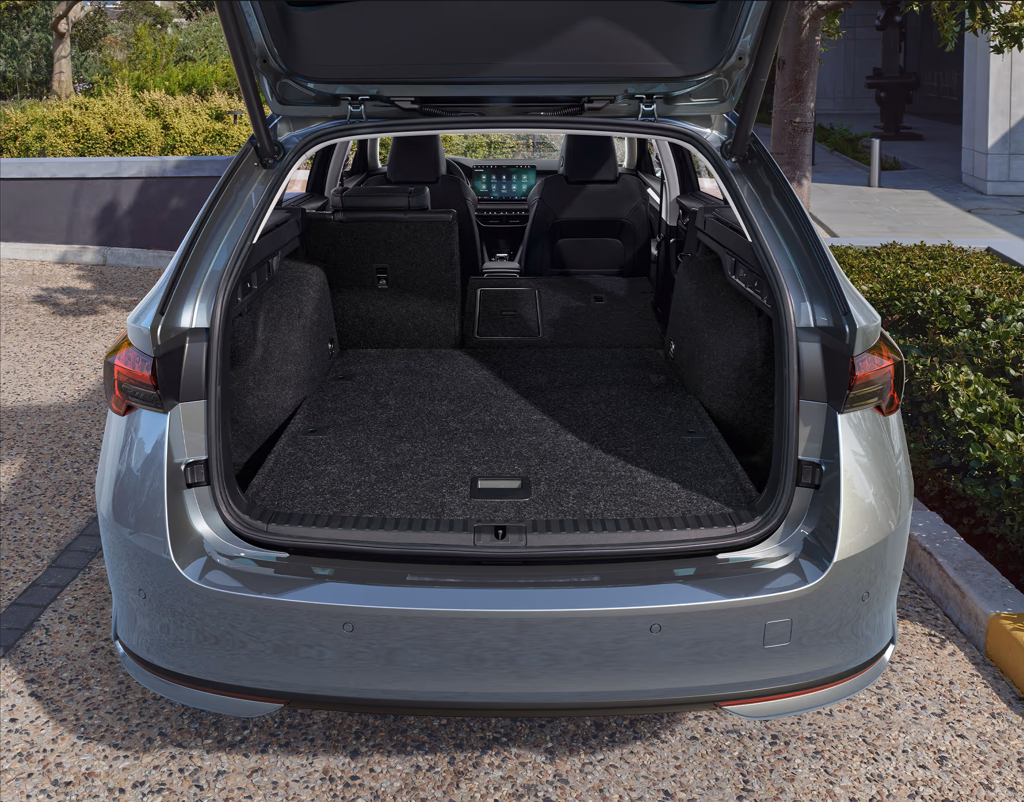 Eine Ansicht des geöffneten Kofferraums eines Škoda Octavia Combi zeigt die teilweise umgeklappte Rücksitzbank. Die mittlere und die rechte Rücksitzlehne sind nach vorne geklappt, um die Ladefläche zu vergrößern, während der linke Sitz aufrecht steht.