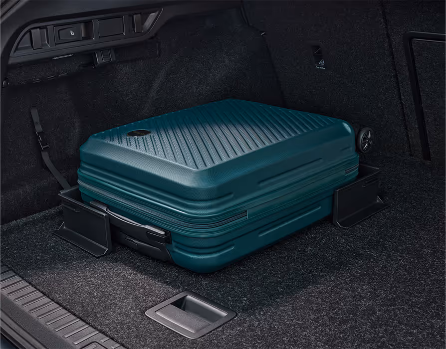 Eine Nahaufnahme des geöffneten Kofferraums eines Škoda Octavia Combi zeigt einen grünen Hartschalenkoffer, der durch zwei schwarze Cargo-Elemente gesichert wird. Diese haften mit Klettverschluss am Kofferraumteppich und verhindern so ein Verrutschen der Ladung.
