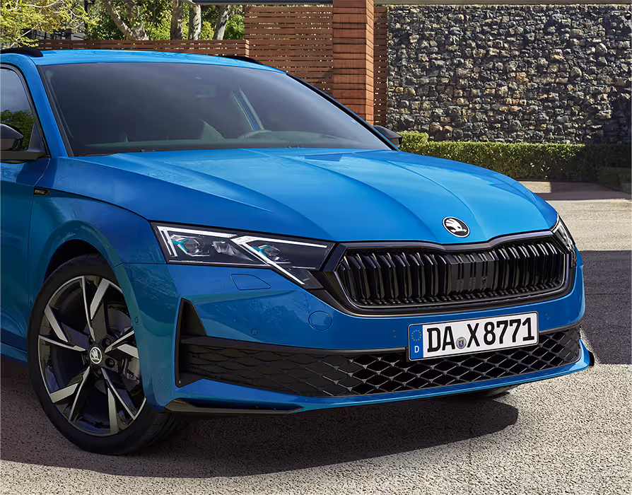 Eine Nahaufnahme zeigt die Frontpartie einer Škoda Octavia Limousine in der Lackierung Race-Blau Metallic. Die Aufnahme hebt die sportlichen Details der Ausstattungslinie Sportline hervor, darunter den schwarz glänzenden Kühlergrill und die Voll-LED-Matrix-Scheinwerfer.